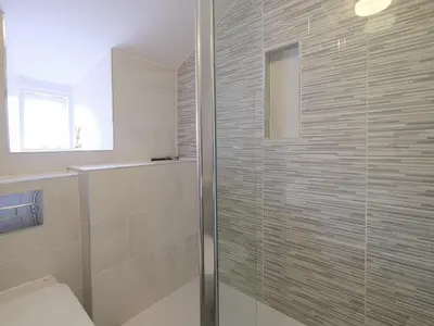 a bathroom with a glass shower with a toilet at Lantern Cottage in St Austell