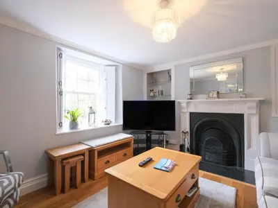 a living room with a tv and a fireplace at Lantern Cottage in St Austell