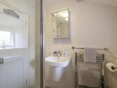 a white bathroom with a sink and a shower at Lantern Cottage in St Austell