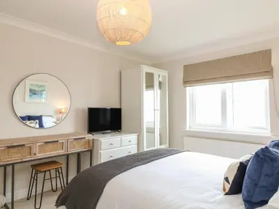 a bedroom with a bed and a desk and a mirror at Breakers in Newquay
