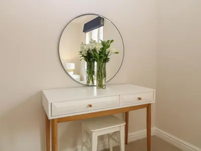 a vase of flowers on a table with a mirror at Breakers in Newquay