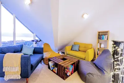 a living room with a blue couch and yellow chairs at Breakers in Newquay