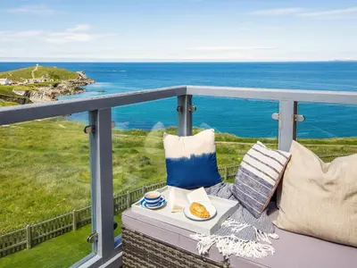 a table with a plate of food on a balcony overlooking the ocean at Breakers in Newquay
