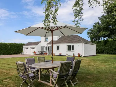 a wooden table with chairs and an umbrella at Trevore Farmhouse in Truro