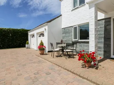 a patio with a table and chairs and flowers at Trevore Farmhouse in Truro