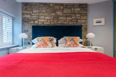 a bedroom with a large bed with a red blanket at Iris 5 Star Gold Award Luxury Cottage in St Ives