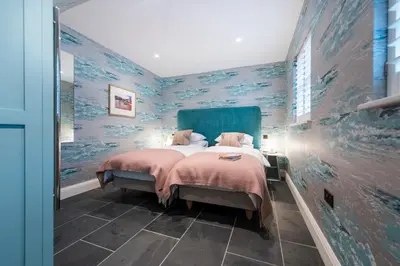 a bedroom with a large bed with blue walls at Iris 5 Star Gold Award Luxury Cottage in St Ives