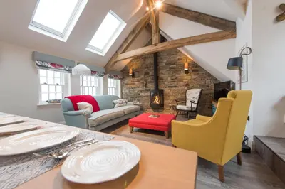 a living room with a table and chairs and a fireplace at Iris 5 Star Gold Award Luxury Cottage in St Ives
