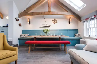 a dining room with a table with a red bench at Iris 5 Star Gold Award Luxury Cottage in St Ives