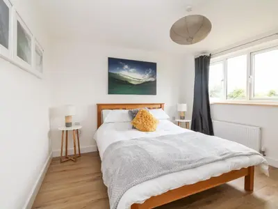 a white bedroom with a bed and a window at Pen Chy in Helston
