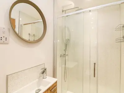 a bathroom with a shower and a sink and a mirror at Pen Chy in Helston