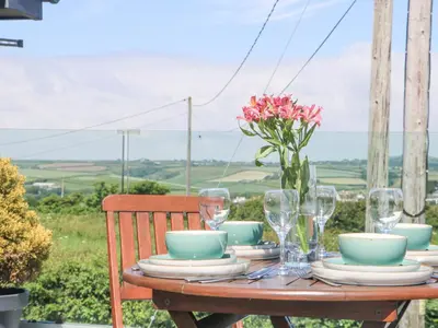 a wooden table with glasses and a vase of flowers on it at Pen Chy in Helston