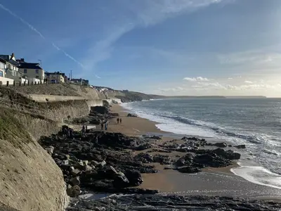 a beach with people standing on the rocks at Pen Chy in Helston