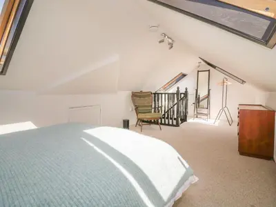 a bedroom with a bed and a chair in a attic at Auverne in Bude