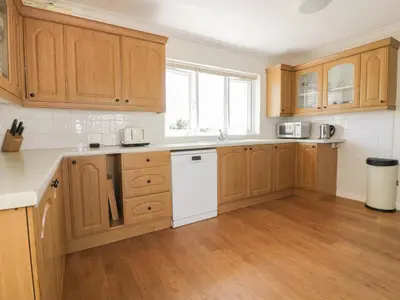 a kitchen with wooden cabinets and a white dishwasher at Auverne in Bude