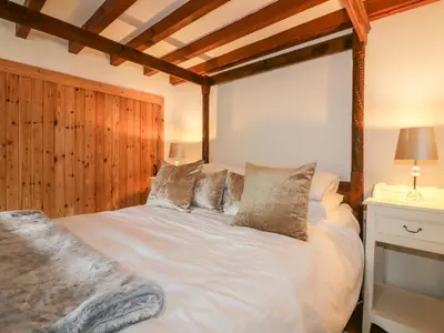 a bedroom with a large white bed with a wooden headboard at Ribby Barn in Lostwithiel