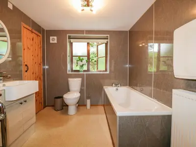 a bathroom with a tub and a toilet and a sink at Ribby Barn in Lostwithiel