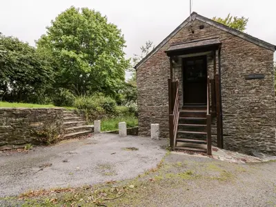 a brick building with a staircase leading to a door at Ribby Barn in Lostwithiel