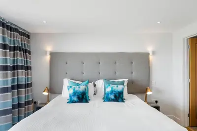 a bedroom with a large white bed with blue pillows at SeaEsta in Portreath