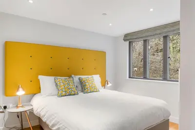a bedroom with a large bed with a yellow headboard at SeaEsta in Portreath