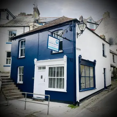 a blue and white building with a sign on it at On Season 4 of BBC 1s BEYOND PARADISE - Prospect House is TWO PRIVATE APARTMENTS in this 17th CENTURY COTTAGE - Apartment 2 has a KIDS CABIN BUNK ROOM - Book both apartments for ONE LARGE HOUSE with Connecting Door In Lobby - FREE PUBLIC PARKING OUTSIDE in Looe