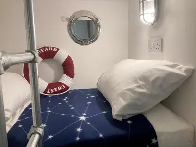 a room with a bed with a pillow and a mirror at On Season 4 of BBC 1s BEYOND PARADISE - Prospect House is TWO PRIVATE APARTMENTS in this 17th CENTURY COTTAGE - Apartment 2 has a KIDS CABIN BUNK ROOM - Book both apartments for ONE LARGE HOUSE with Connecting Door In Lobby - FREE PUBLIC PARKING OUTSIDE in Looe