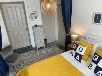 a bedroom with a yellow bed and a chair at On Season 4 of BBC 1s BEYOND PARADISE - Prospect House is TWO PRIVATE APARTMENTS in this 17th CENTURY COTTAGE - Apartment 2 has a KIDS CABIN BUNK ROOM - Book both apartments for ONE LARGE HOUSE with Connecting Door In Lobby - FREE PUBLIC PARKING OUTSIDE in Looe