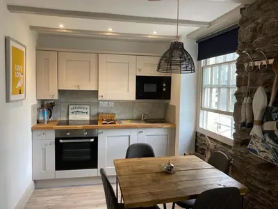a kitchen with a wooden table and a dining room at On Season 4 of BBC 1s BEYOND PARADISE - Prospect House is TWO PRIVATE APARTMENTS in this 17th CENTURY COTTAGE - Apartment 2 has a KIDS CABIN BUNK ROOM - Book both apartments for ONE LARGE HOUSE with Connecting Door In Lobby - FREE PUBLIC PARKING OUTSIDE in Looe