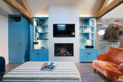a living room with blue cabinets and a fireplace at Wella 5 Star Gold Award Luxury Cottage in St Ives