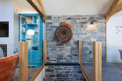 a stone wall in a living room with a blue cabinet at Wella 5 Star Gold Award Luxury Cottage in St Ives