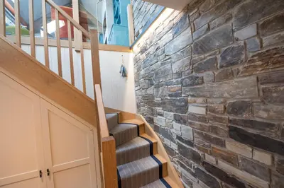 a staircase in a house with a stone wall at Wella 5 Star Gold Award Luxury Cottage in St Ives