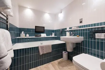 a bathroom with green and white tiled walls and a sink at Wella 5 Star Gold Award Luxury Cottage in St Ives
