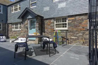 a table and two stools in front of a building at Wella 5 Star Gold Award Luxury Cottage in St Ives