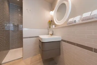 a bathroom with a sink and a mirror and a shower at Wella 5 Star Gold Award Luxury Cottage in St Ives