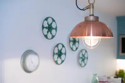 a light fixture hanging on a wall with clocks at Juliot 5 Star Gold Award Luxury Cottage in St Ives