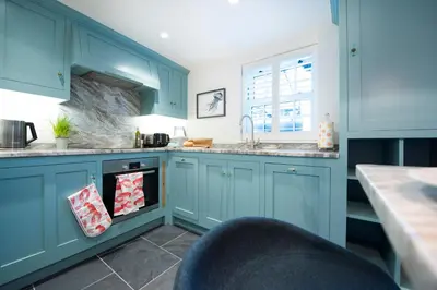 a kitchen with blue cabinets and a sink at Juliot 5 Star Gold Award Luxury Cottage in St Ives
