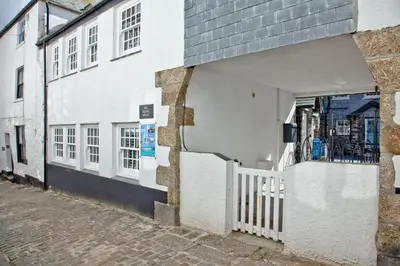 a white building with a white fence next to a street at Juliot 5 Star Gold Award Luxury Cottage in St Ives