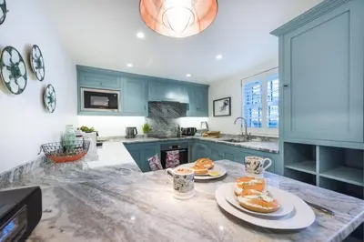 a kitchen with blue cabinets and plates of food on a counter at The Garth 5 Star Gold Luxury Cottages in St Ives