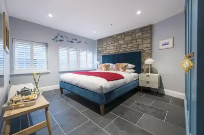 a bedroom with a blue bed and a stone wall at The Garth 5 Star Gold Luxury Cottages in St Ives