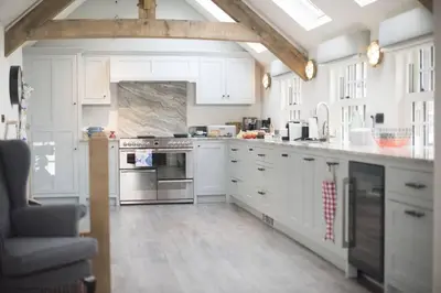a kitchen with white cabinets and a stove top oven at The Garth 5 Star Gold Luxury Cottages in St Ives