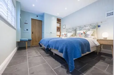 a bedroom with a large bed with blue walls at The Garth 5 Star Gold Luxury Cottages in St Ives