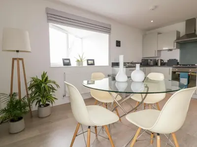 a dining room with a glass table and white chairs at The Lookout in Newquay