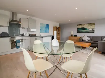a kitchen and living room with a glass table and chairs at The Lookout in Newquay