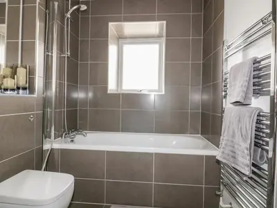 a bathroom with a tub and a toilet and a window at The Lookout in Newquay