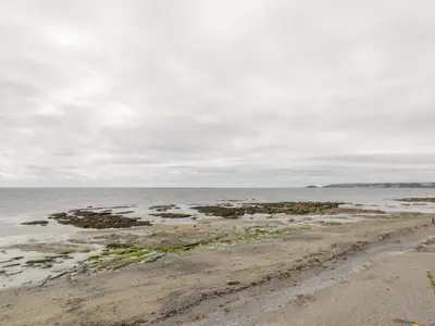 a beach with rocks in the water on a cloudy day at The Bolt Hole in Torpoint
