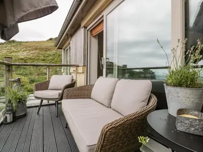 a wicker couch sitting on a screened in porch at The Bolt Hole in Torpoint