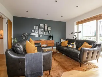 a living room with two black leather couches and yellow pillows at The Bolt Hole in Torpoint