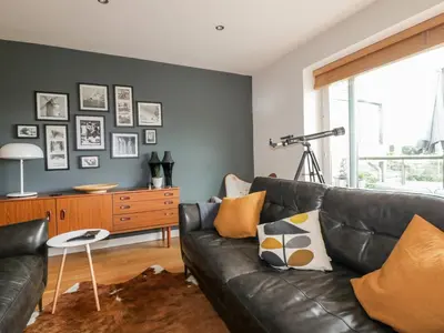 a living room with a black leather couch at The Bolt Hole in Torpoint