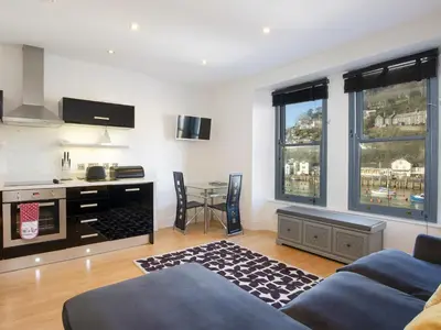 a living room with a couch and a table at Water View in Looe