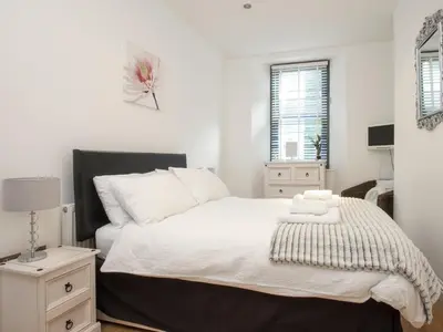 a bedroom with a bed with white sheets and a window at Water View in Looe